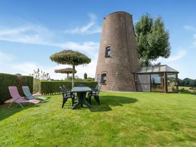 a building with a table and chairs in the grass at Charming Nieuwpoort Mill Retreat in Zottegem