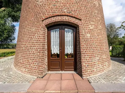 a brick building with a large wooden door at Charming Nieuwpoort Mill Retreat in Zottegem