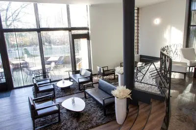 a lobby with chairs and tables and a large window at Best Western Plus Aldhem Hotel in Grobbendonk