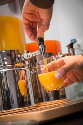 a person pouring an orange juice into a glass at Let's Meet Elewijt in Elewijt