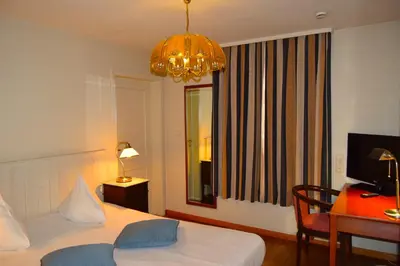 a bedroom with a bed and a desk and a chandelier at Oranje City Hotel in Diest