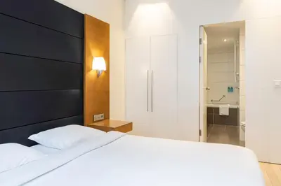 a bedroom with a white bed and a shower at B-aparthotel Grand Place in Brussels