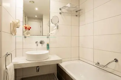 a white bathroom with a sink and a tub at B-aparthotel Grand Place in Brussels