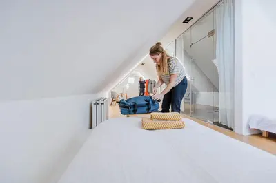 a woman is standing in a room with a blue bag at Viktoria Guesthouse in Westerlo