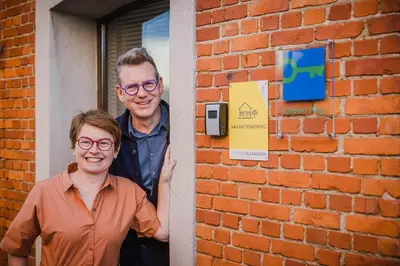 a man and a woman standing next to a brick wall at Viktoria Guesthouse in Westerlo
