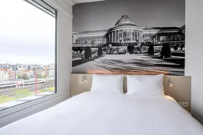 a bedroom with a large white bed and a large window at B&B HOTEL Brussels Centre Gare du Midi in Brussels