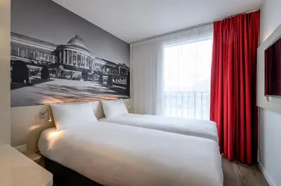 a hotel room with two beds and a red curtain at B&B HOTEL Brussels Centre Gare du Midi in Brussels