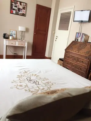 a bedroom with a bed and a table and a dresser at B&B Chambre Chocolat in Brussels