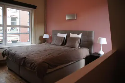 a bedroom with a bed with two lamps and a window at All Inn Holiday Home in Ghent