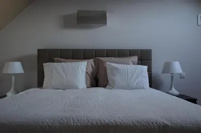 a bedroom with a bed with white sheets and pillows at All Inn Holiday Home in Ghent