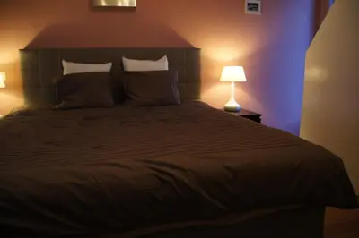 a bedroom with a large bed and a lamp at All Inn Holiday Home in Ghent