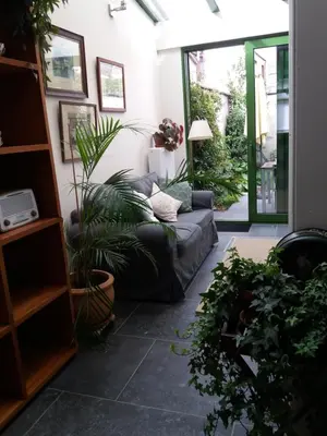 a living room with a couch and some plants at Quiet apartment in Antwerp near parc - B&B InterMezzo - business & leisure in Antwerp