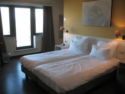 a bedroom with a large bed with white sheets and pillows at B&B La Vie En Roses in Moorsel