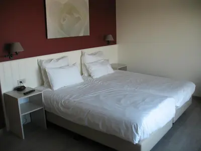 a bedroom with a large bed with white sheets and pillows at B&B La Vie En Roses in Moorsel