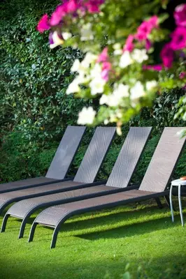 a row of benches sitting in the grass with flowers at Hotel Thermen Mineraal in Rijmenam