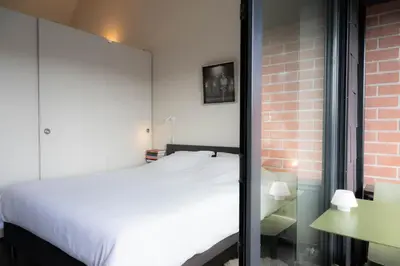 a bedroom with a white bed and a brick wall at Designflats Gent in Ghent