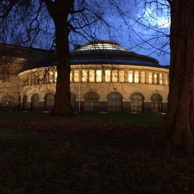 a building lit up at night with trees in the foreground at Designflats Gent in Ghent