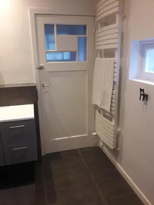 a bathroom with a white door and a window at Un grand jardin en ville. Chez Guy in Brussels