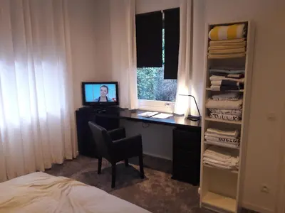 a room with a desk with a computer and a television at Un grand jardin en ville. Chez Guy in Brussels
