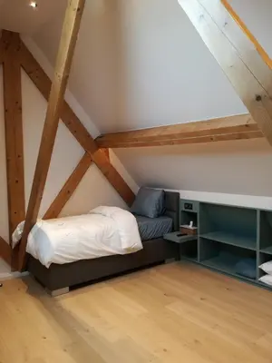 a bed in a loft with wooden beams at B&B Hof ter Kouter in Dworp