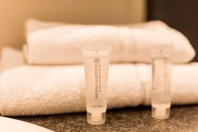 a pile of white towels and two tubes of sunscreen at Diamant Suites Brussels EU in Brussels