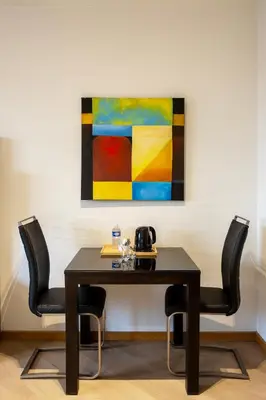 a table with two chairs and a painting on the wall at Diamant Suites Brussels EU in Brussels