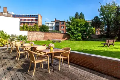 a row of wooden tables and chairs on a patio at Diamant Suites Brussels EU in Brussels
