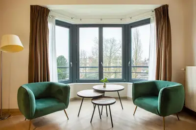 a living room with two chairs and a table and a window at Diamant Suites Brussels EU in Brussels