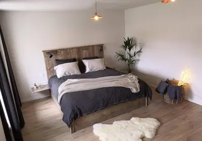 a bedroom with a large bed with a wooden headboard at Bed en Bezem in Laarne