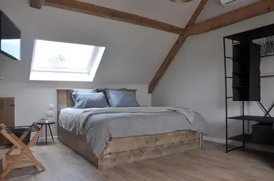 a bedroom with a large bed and a window at Bed en Bezem in Laarne