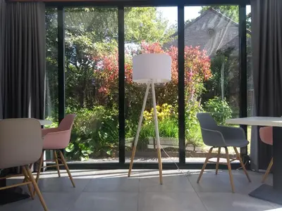 a room with chairs and a lamp in front of a window at Pluimpapaver Hotel & Glamping in Aarschot