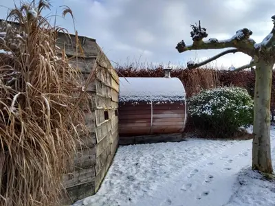 a snow covered backyard with a wooden fence and ashed at Pluimpapaver Hotel & Glamping in Aarschot