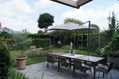 a patio with a table and chairs and an umbrella at B&B Het Wouwe in Herentals