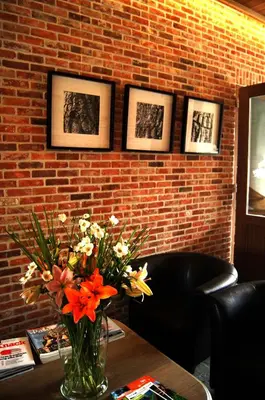 a vase of flowers on a table with pictures on a brick wall at B&B Het Wouwe in Herentals