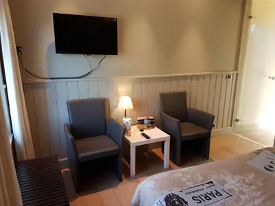 a room with two chairs and a table and a tv at B & B DE SERAFIJN in Lochristi