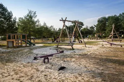 an empty playground with a bench in the sand at Safaritent at Camping GT Keiheuvel in Balen