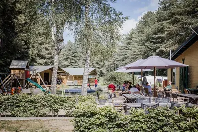 a group of people sitting at a table with an umbrella at Camping Siësta in Lille