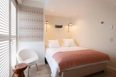 a white bedroom with a bed and a chair at Made in Catherine in Brussels
