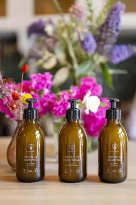 three bottles of soap sitting on a table with flowers at Made in Catherine in Brussels