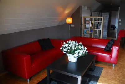 a living room with a red couch and a table with flowers at De Rosmolen in Ertvelde