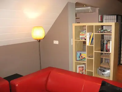 a red couch in a living room with a book shelf at De Rosmolen in Ertvelde