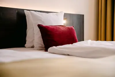 a bed with a red pillow and white pillows at Corsendonk Turnova in Turnhout