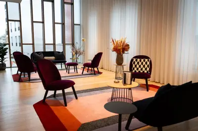 a living room with chairs and tables and windows at Corsendonk Turnova in Turnhout