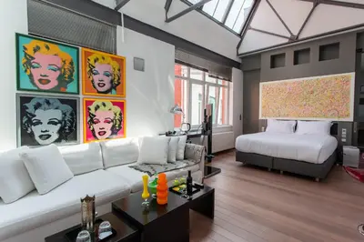 a living room with a white couch and a bed at Les Lofts d'Artistes in Brussels
