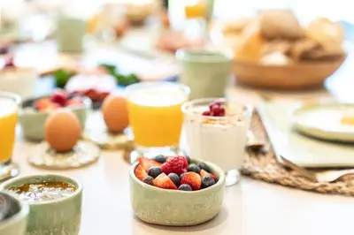 a table topped with bowls of fruit and orange juice at De Gulle Beemden in Hulshout