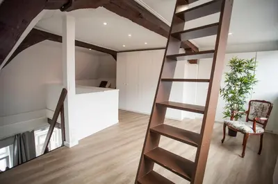 a loft conversion with a ladder and a living room at Luxury Suites Cathedral by Rikas Hotels in Antwerp