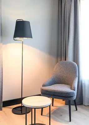 a room with a chair and a lamp and a table at Radisson Hotel Antwerp Berchem in Antwerp