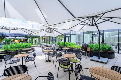 an outdoor patio with tables and chairs and umbrellas at Radisson Hotel Antwerp Berchem in Antwerp