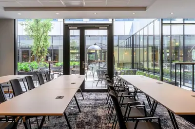 a row of tables and chairs in a room with windows at Radisson Hotel Antwerp Berchem in Antwerp