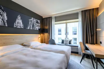 a hotel room with two beds and a desk at Radisson Hotel Antwerp Berchem in Antwerp